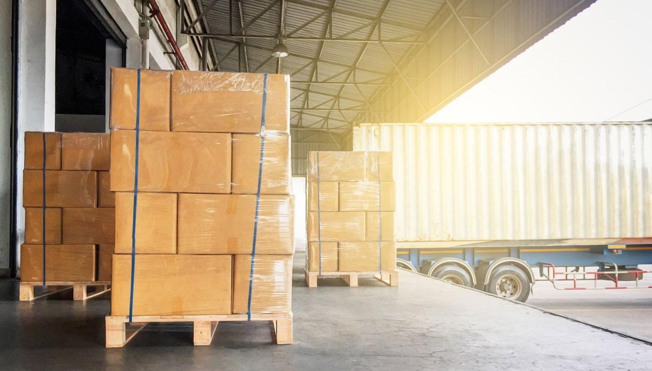 Palettes de cartons filmées sur un quai de chargement, devant la remorque d'un camion